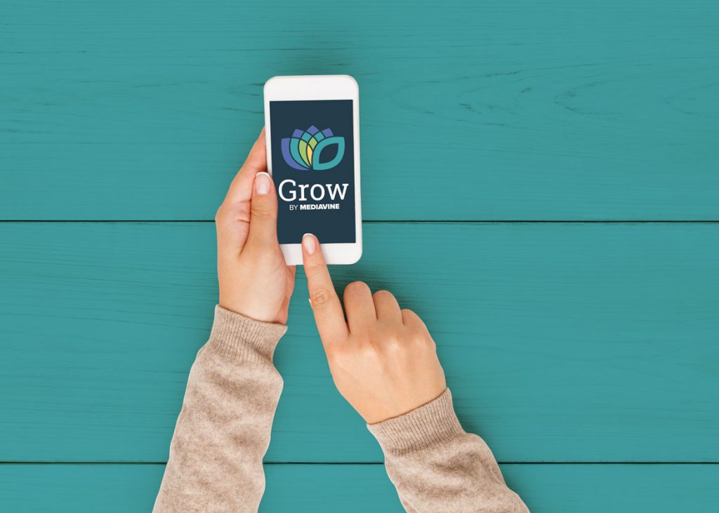 hands using a phone displaying the grow by mediavine logo on a teal background
