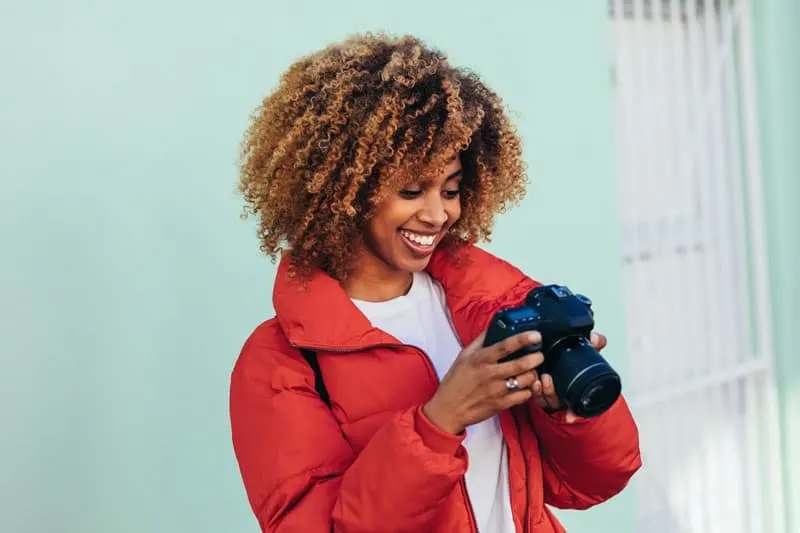 woman in a red jacket looking at photos on her camera