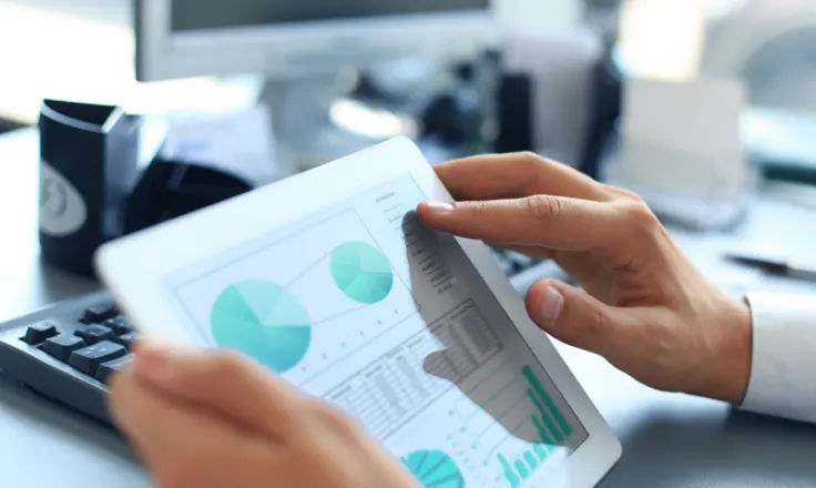 business person with hands on ipad displaying pie charts and graphs