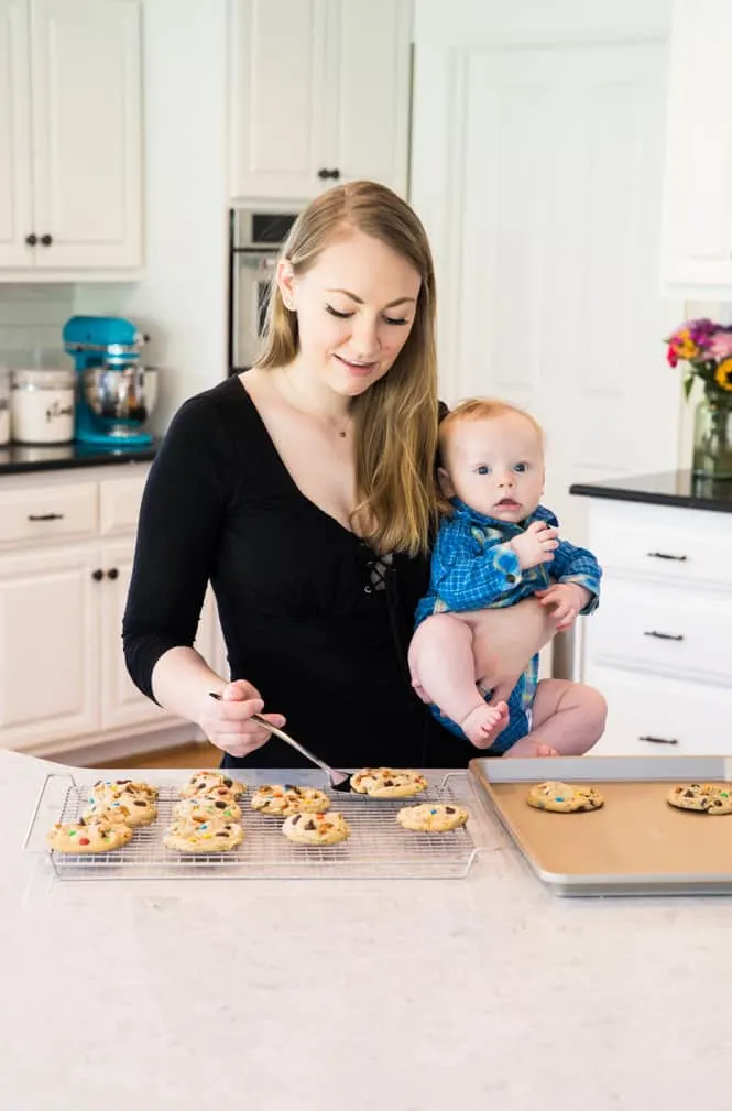 Sam of Sugar Spun Run holding baby Luke with cookies on a tray