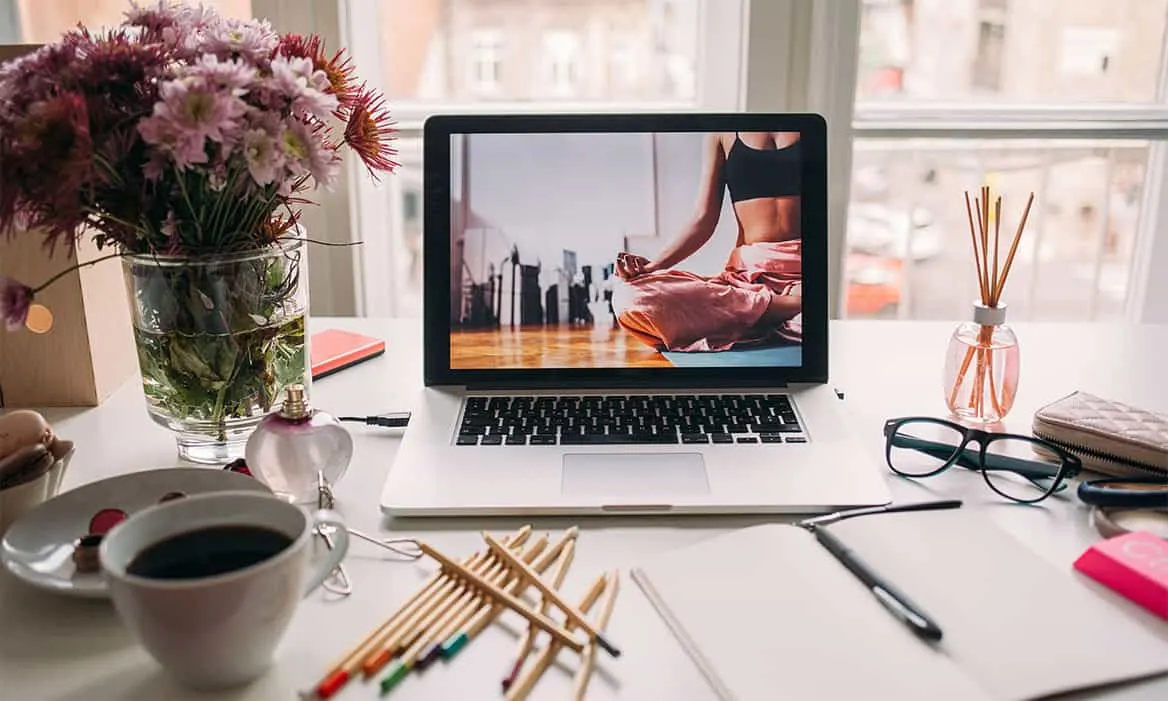 laptop with yoga video with pens and paper in front