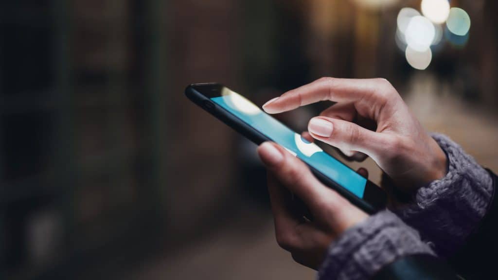 woman's hands scrolling a website on a mobile phone at night