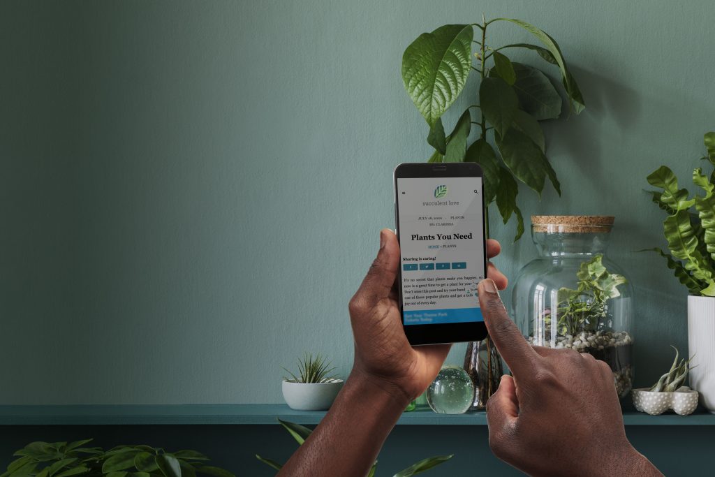 hands using grow on a website in a room full of plants
