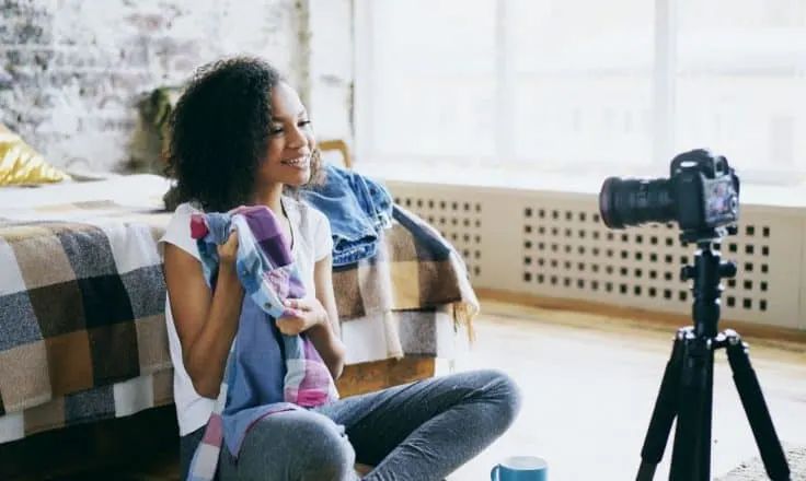 young female fashion blogger showing off a colorful plaid shirt to a video camera