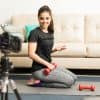 female fitness blogger filming an exercise video on a yoga mat in her living room
