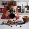female food blogger photographing fresh produce on a gray napkin in her kitchen