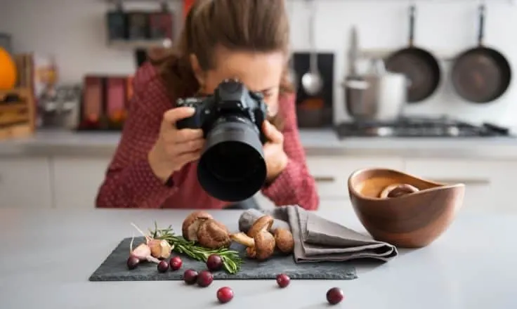 female food blogger photographing fresh produce on a gray napkin in her kitchen
