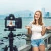 female travel blogger filming a travel video on a bridge with skyline behind her