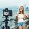 female travel blogger filming a travel video on a bridge with skyline behind her