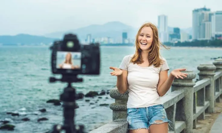 female travel blogger filming a travel video on a bridge with skyline behind her