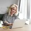 woman at office desk on laptop next to glasses and coffee