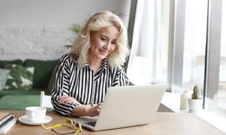 woman at office desk on laptop next to glasses and coffee