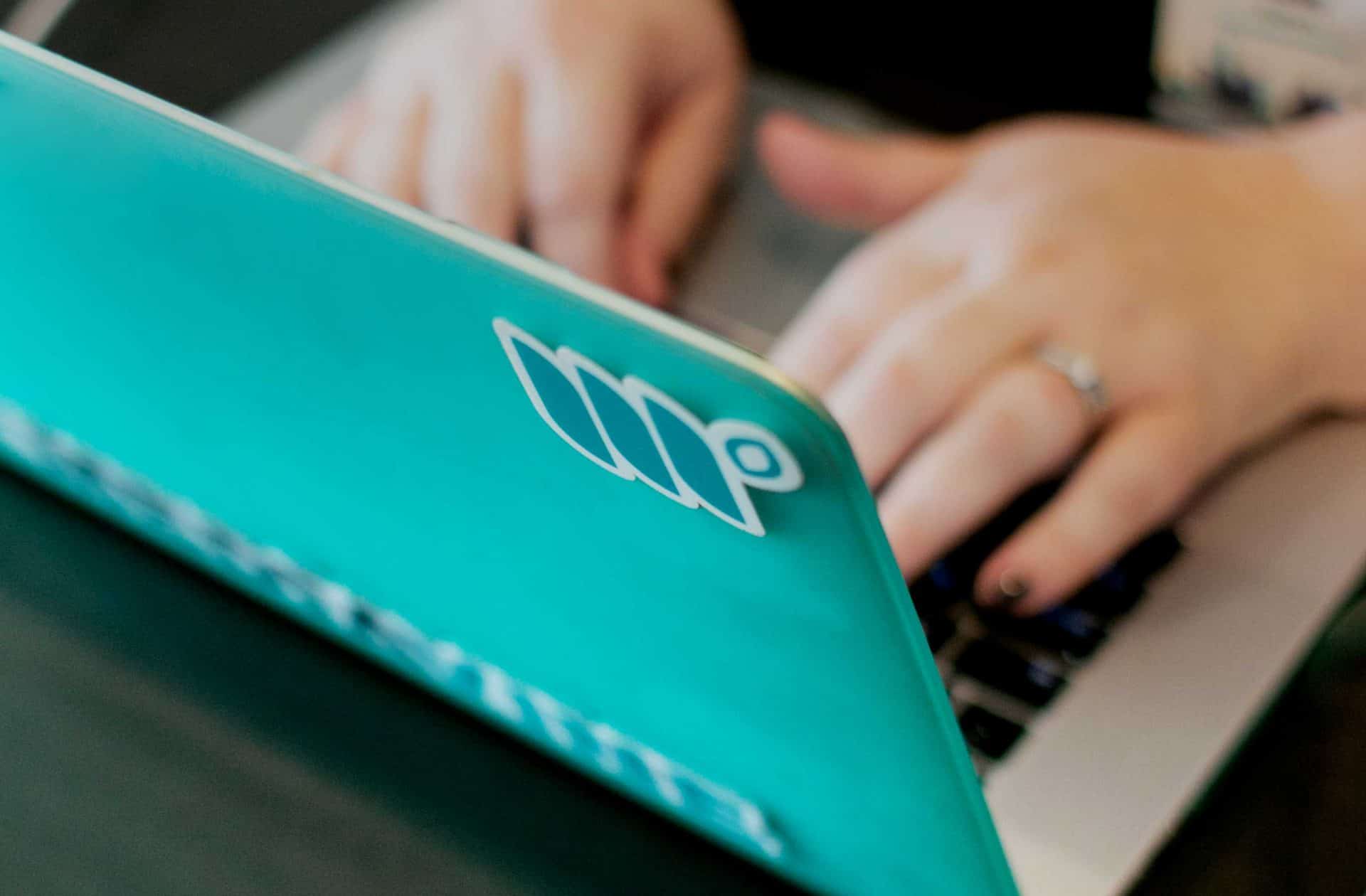 woman's hands typing on a teal computer covered in Mediavine stickers
