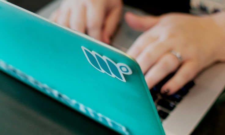 woman's hands typing on a teal computer covered in Mediavine stickers