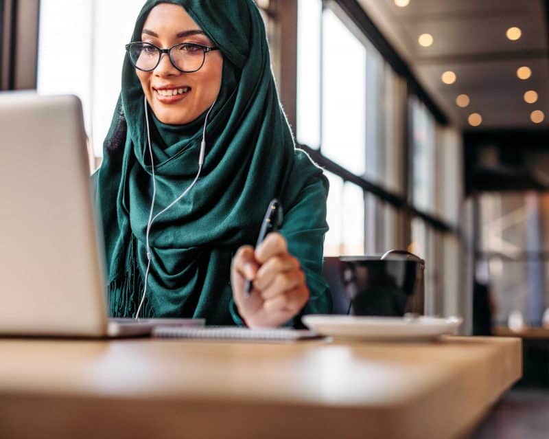 woman wearing headscarf blogging in a cafe