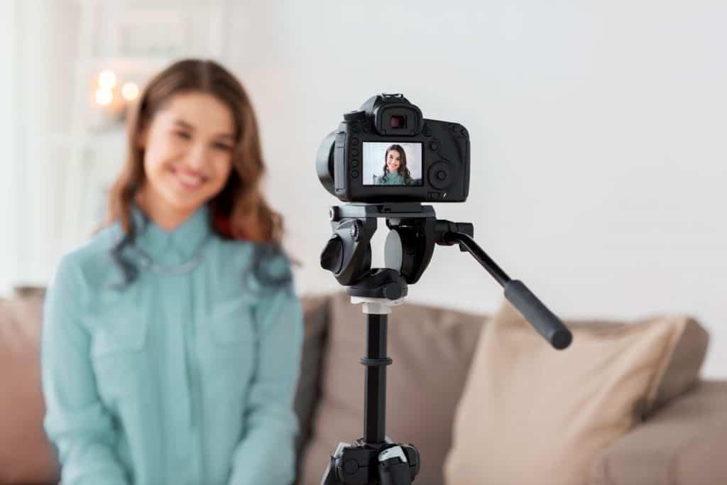 woman in aqua shirt filming a video for her blog