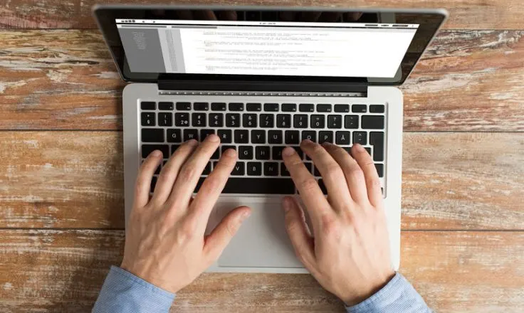 above view of person's hands typing on a laptop