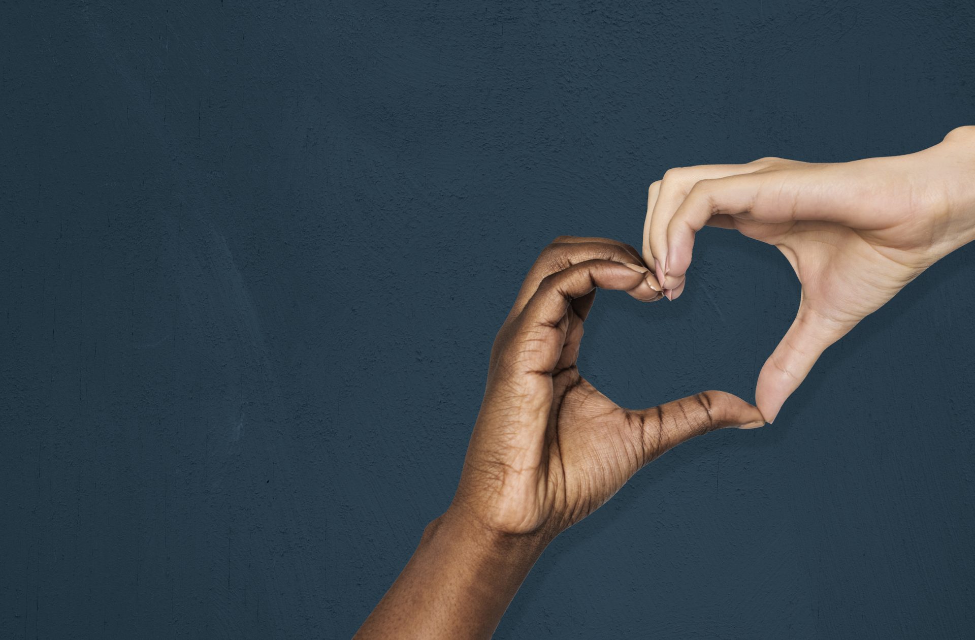 multiracial hands forming a heart shape