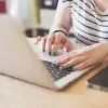 woman sitting at desk typing on laptop