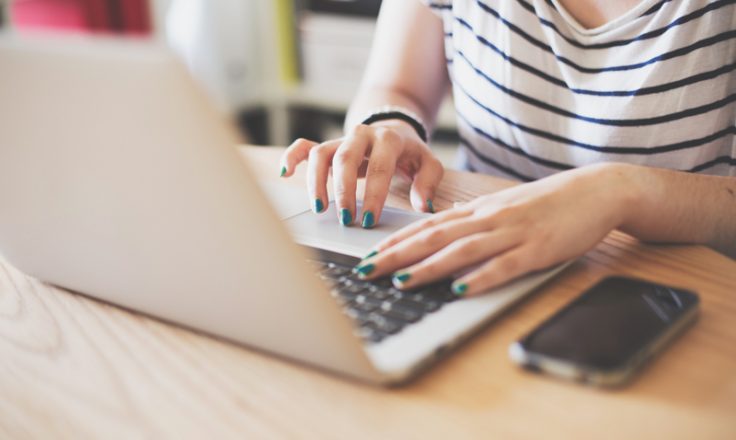 woman sitting at desk typing on laptop