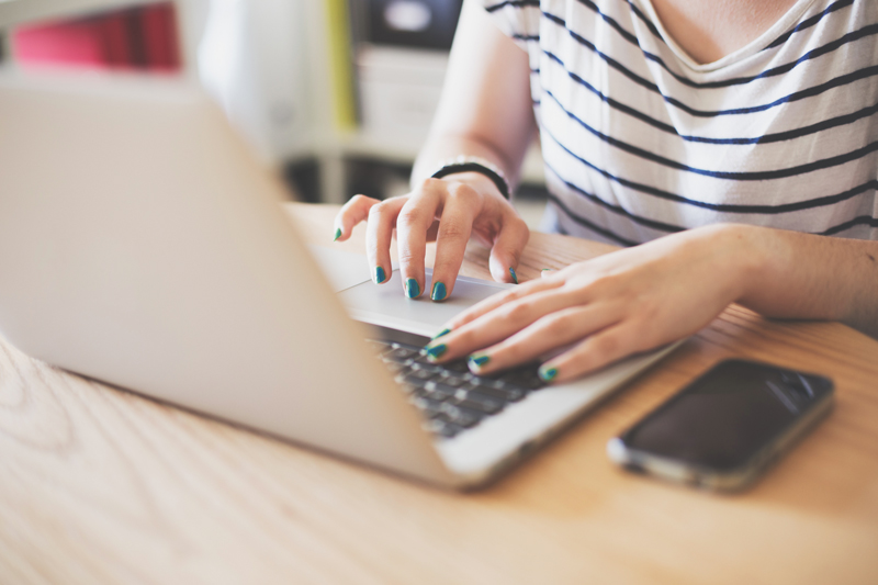 woman sitting at desk typing on laptop
