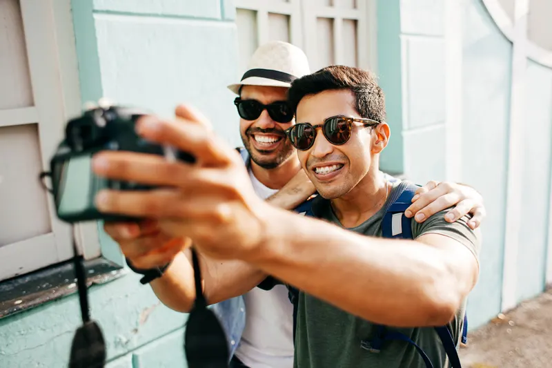 two men posing for a picture holding a camera