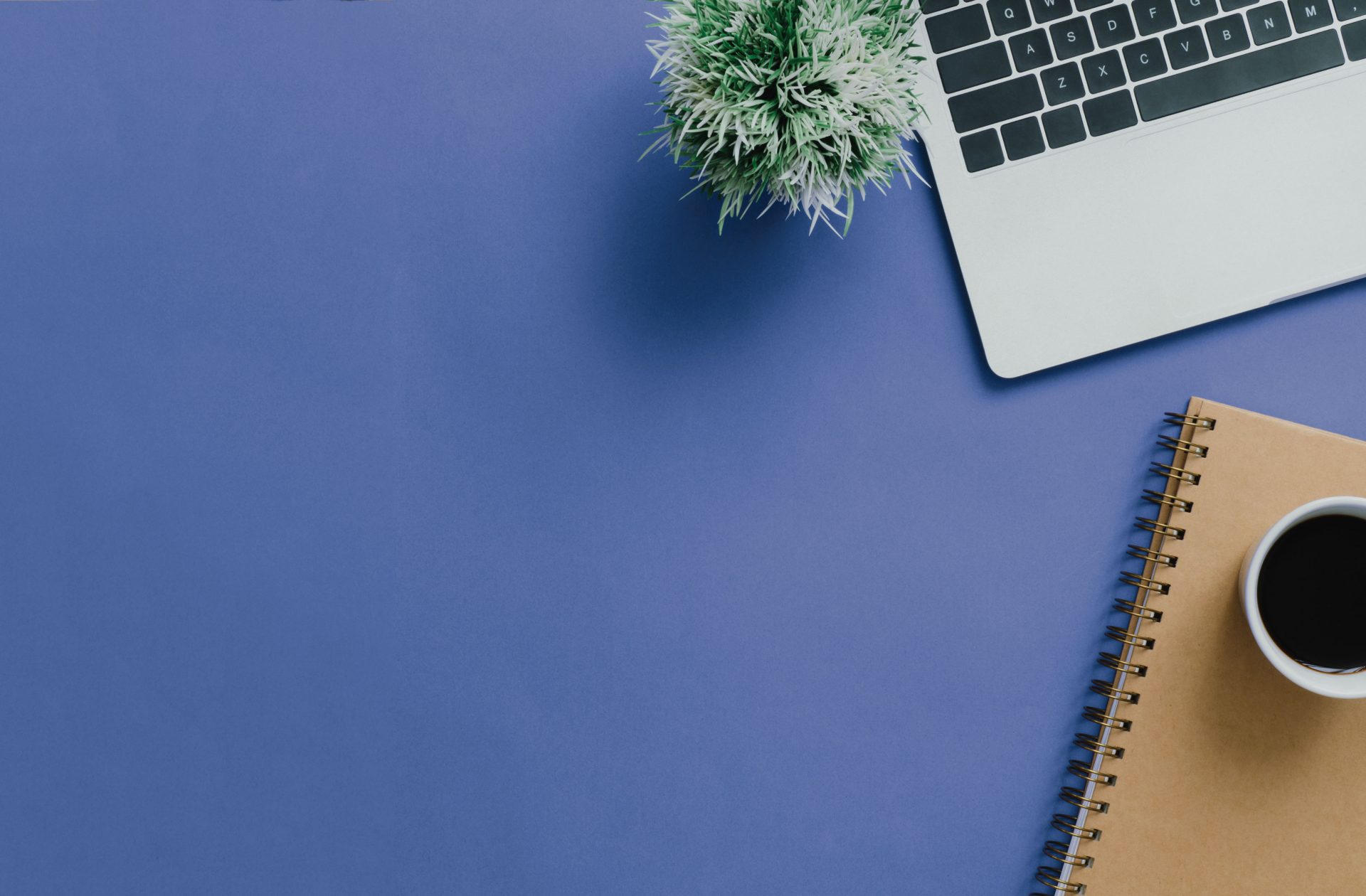 computer and notebook and coffee mug sitting on a periwinkle background