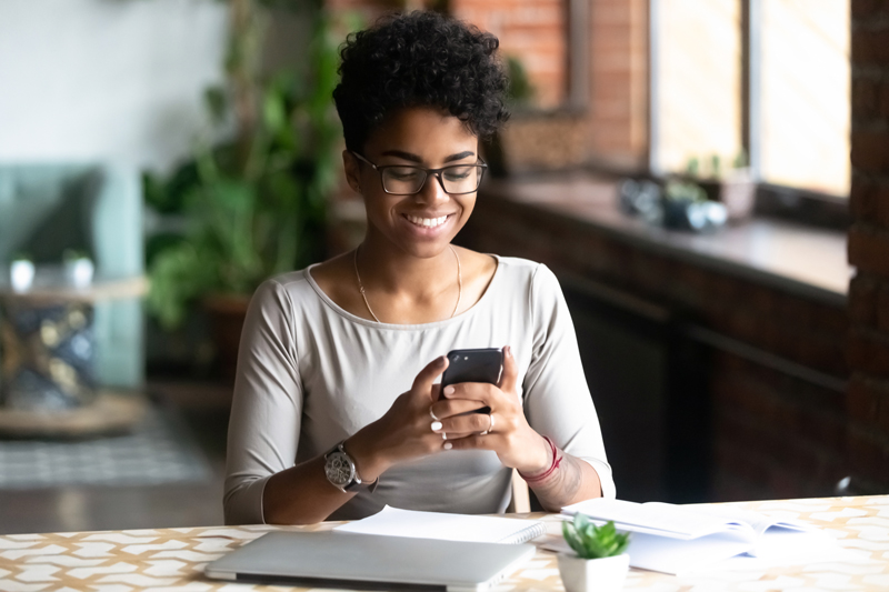 woman smiling at phone sitting at table