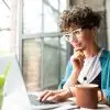 woman thinking and reading on laptop