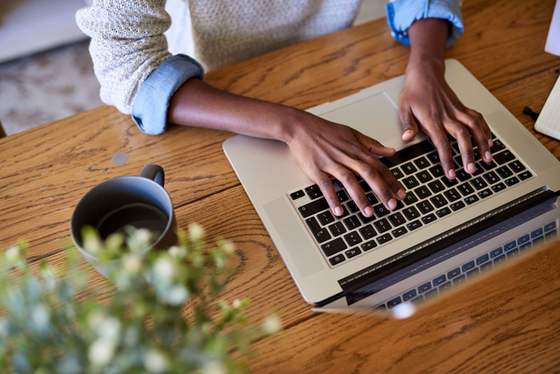 hands typing on laptop on a wooden table