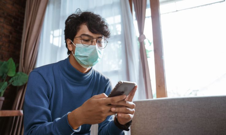 person wearing mask using phone