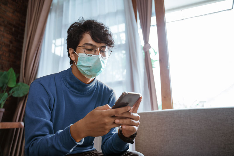 person wearing mask using phone