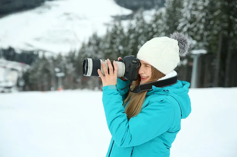 woman using a camera in the snow to film a winter scene