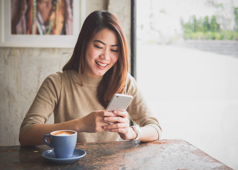 woman smiling at phone at a cafe