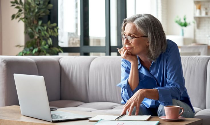 woman wearing glasses looking at laptop