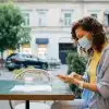 woman wearing a mask, sitting outside using her phone