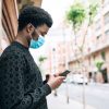 man looking at phone wearing mask