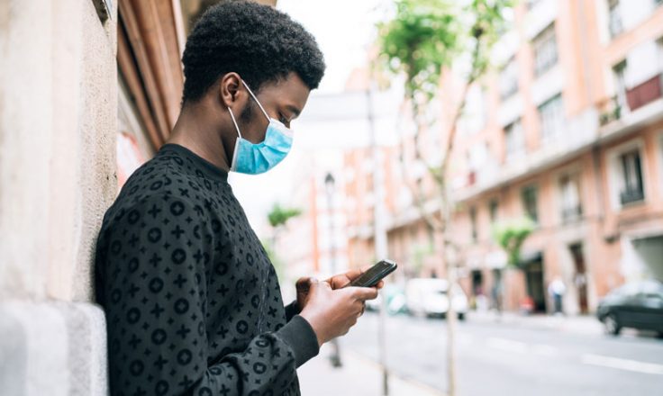 man looking at phone wearing mask