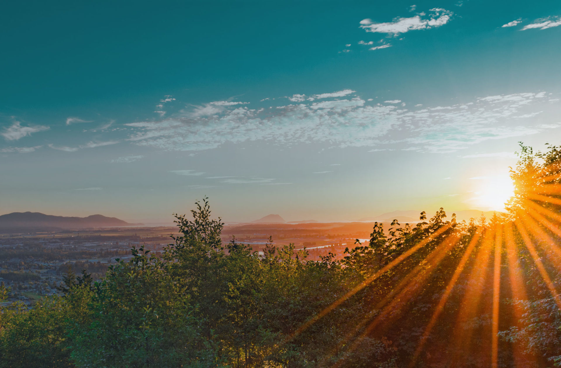 scene of a sun rising over mountains and trees