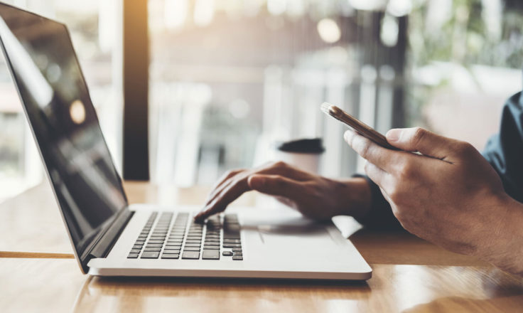 side view of person using phone and laptop