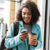 woman smiling at phone holding coffee