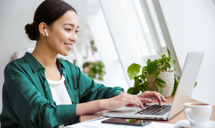 woman using laptop wearing earbuds