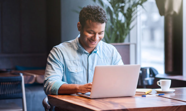 man on laptop sitting in a cafeteria