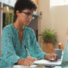 woman using laptop and taking notes