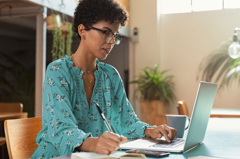 woman using laptop and taking notes