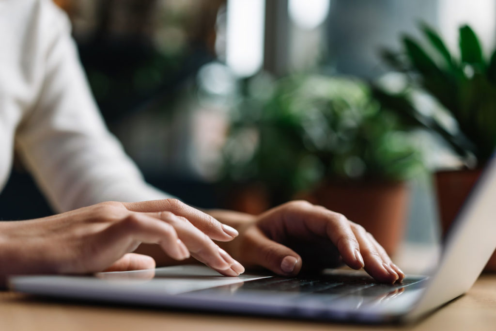 a person's hands browsing the web with grow.me on a laptop computer next to potted plants.
