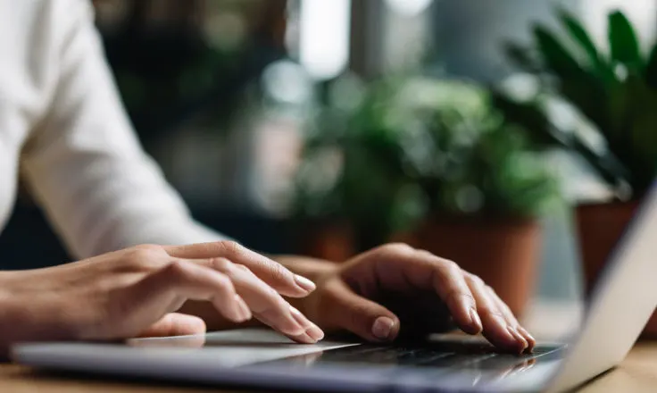 a person's hands browsing the web with grow.me on a laptop computer next to potted plants.