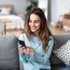 woman sitting on couch using phone