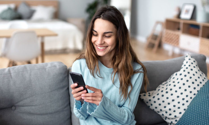 woman sitting on couch using phone