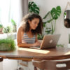 woman using computer surrounded by plants